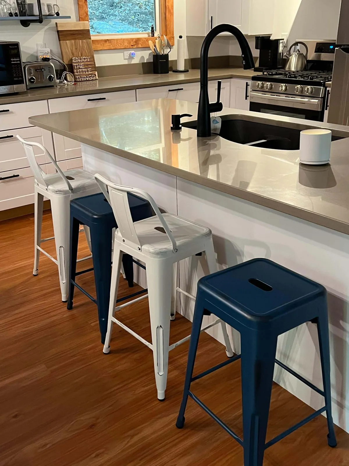 Bar stools lined up at a kitchen island, with a window letting in morning light. The scene highlights a welcoming spot for breakfast or a casual drink while keeping the cook company.