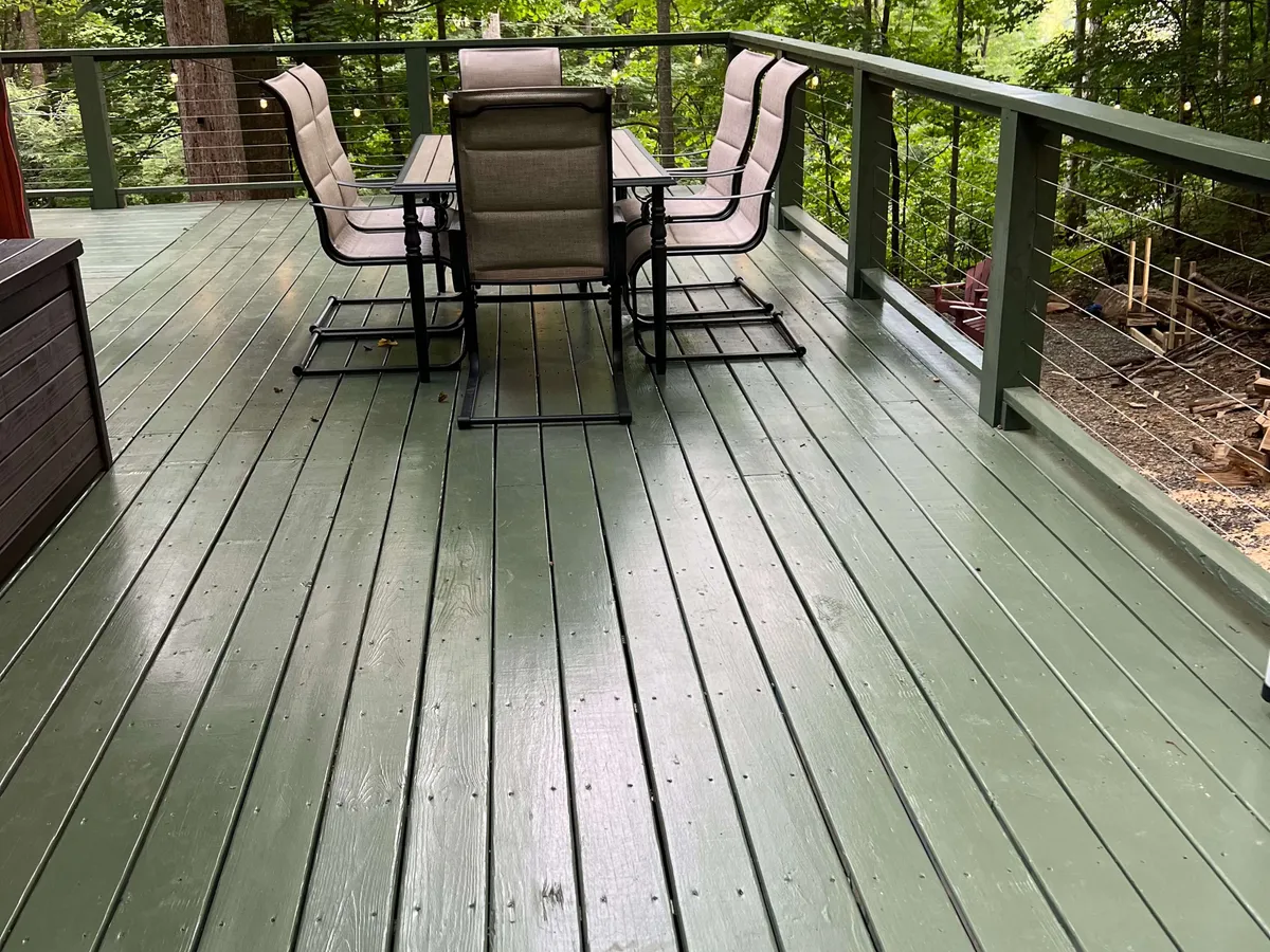 This image shows a spacious wooden deck furnished with a dining table and chairs, ideal for outdoor gatherings. The setting captures the sense of openness and invites relaxation, offering views of the surrounding greenery and an atmosphere perfect for sunset dinners or stargazing.